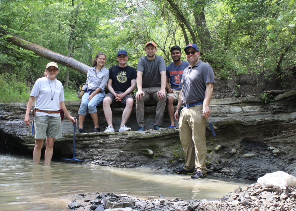 Group of researchers sitting on an outcrop along a small creek